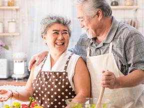 Happy senior couple preparing salad in kitchen