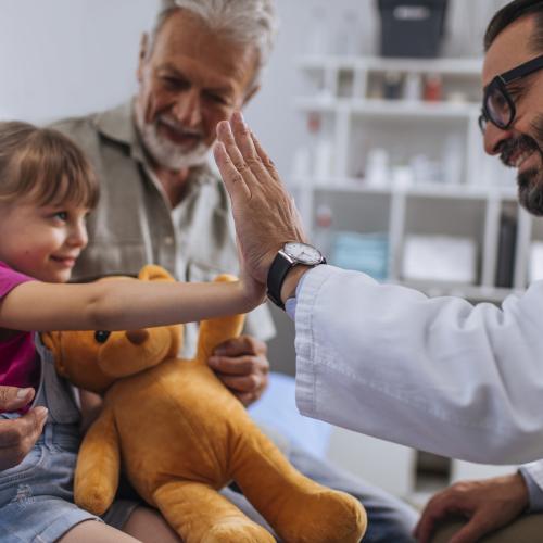 Grand daughter holding yellow teddy bear at doctor visit with her grand father