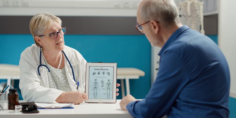 Nurse practitioner showing tablet computer to patient with diagnosis information