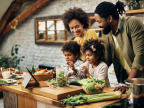 A happy family cooking veggies in a kitchen