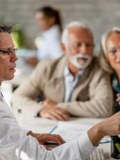 man pointing to screen explaining to older couple