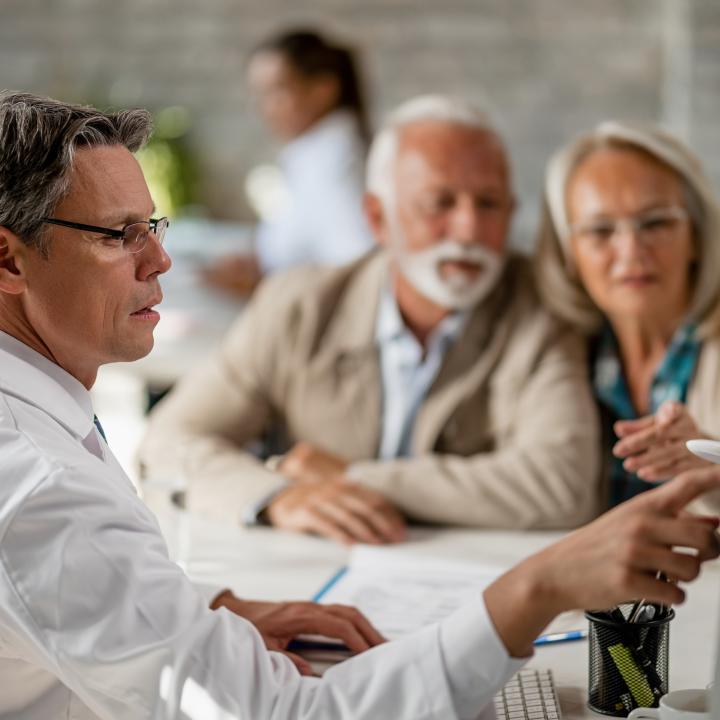 man pointing to screen explaining to older couple