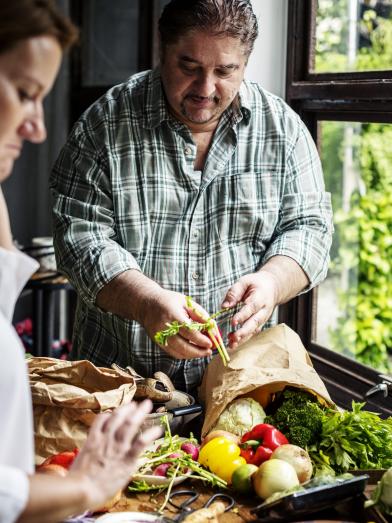 Husband and wife preparing vegetables in kitchen