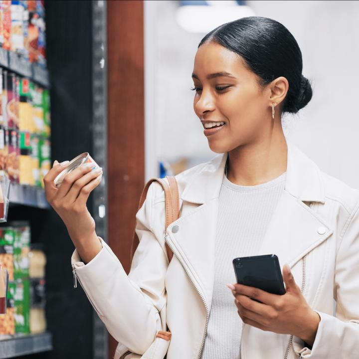 Young woman reading food label on can in grocery store