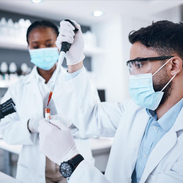 scientific research team testing vial of blood in laboratory