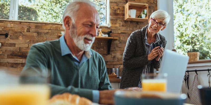 Senior couple reading news on laptop