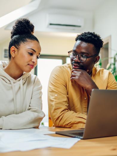 Young couple doing paperwork in front of laptop computer