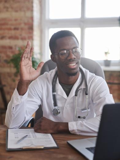 Doctor greeting patient over video call on computer