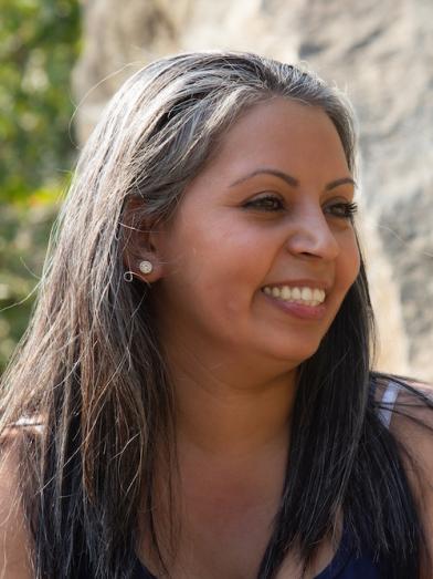 Smiling Hispanic woman outside next to rocks