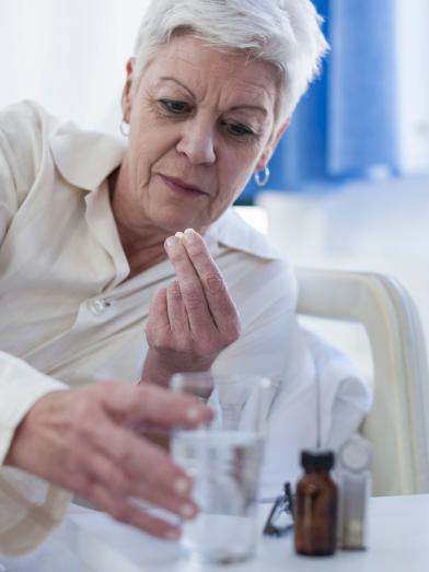 Senior woman in bed taking medication