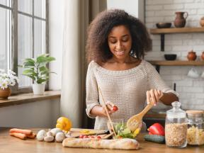 African American woman preparing salad in kitchen