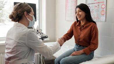 Smiling Latina shaking hands with her doctor at appointment