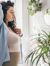 Plump woman in bathroom looking at herself in the mirror