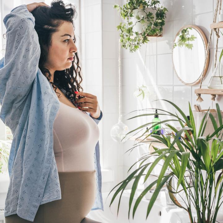 Plump woman in bathroom looking at herself in the mirror