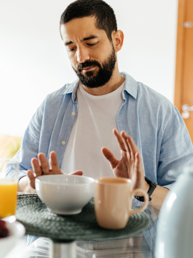 A man pushes away food because he is full. 