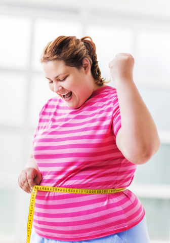 A woman is excited as she measures her waist.