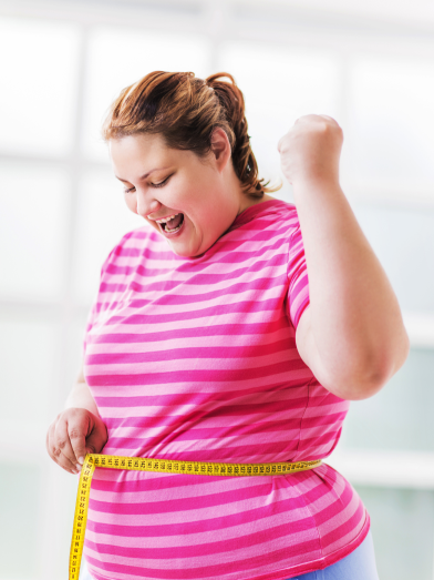 A woman is excited as she measures her waist.