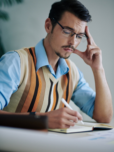 A man sits in front of a notebook and journals.