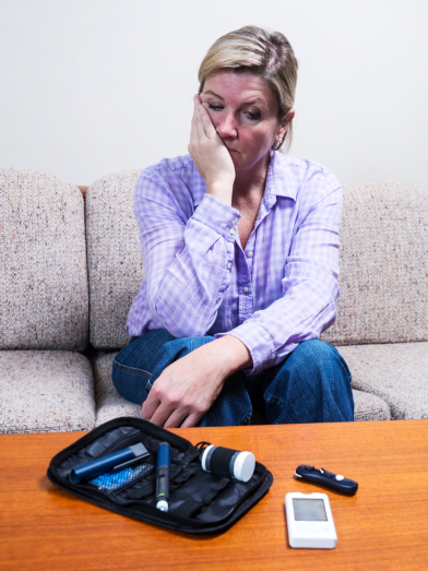 A woman looks sadly at her blood glucose monitor.