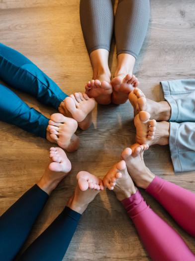 People laying on floor with bare feet in a circle