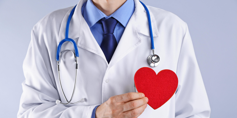 a doctor holding a red papercut heart shape