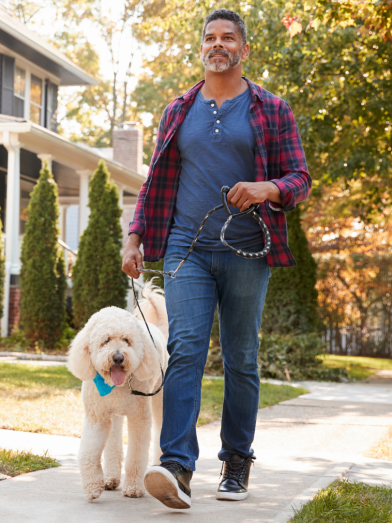 A man walks his dog outside. 