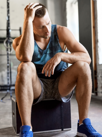 A tired man sits at the gym.