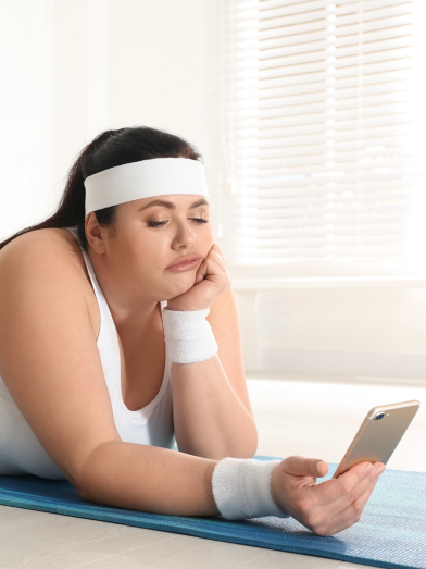 A woman in workout clothes looks at her phone.