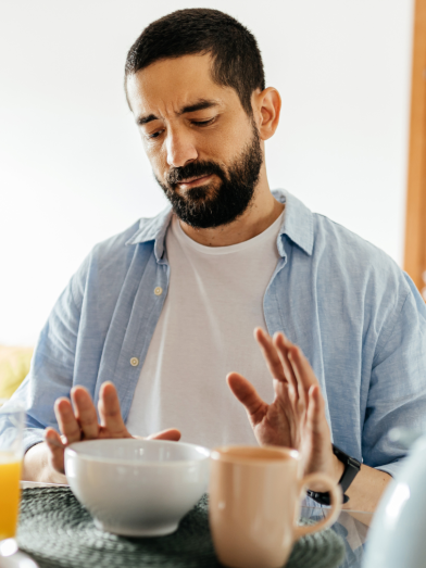 A man pushes away food because he is full. 