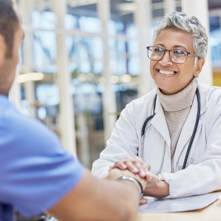 Smiling female physician holding hand of patient